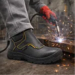 Botas de soldador pretas com costura amarela durante operação de soldadura com faíscas