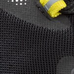 Detalhe da malha respirável preta com apontamentos amarelos no sistema de atacadores