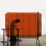 Biombo de soldadura Flex 4000 com cortina laranja suspensa, usado durante operação de soldadura.