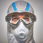 Óculos de segurança panorâmicos usados com fato de proteção e máscara respiratória